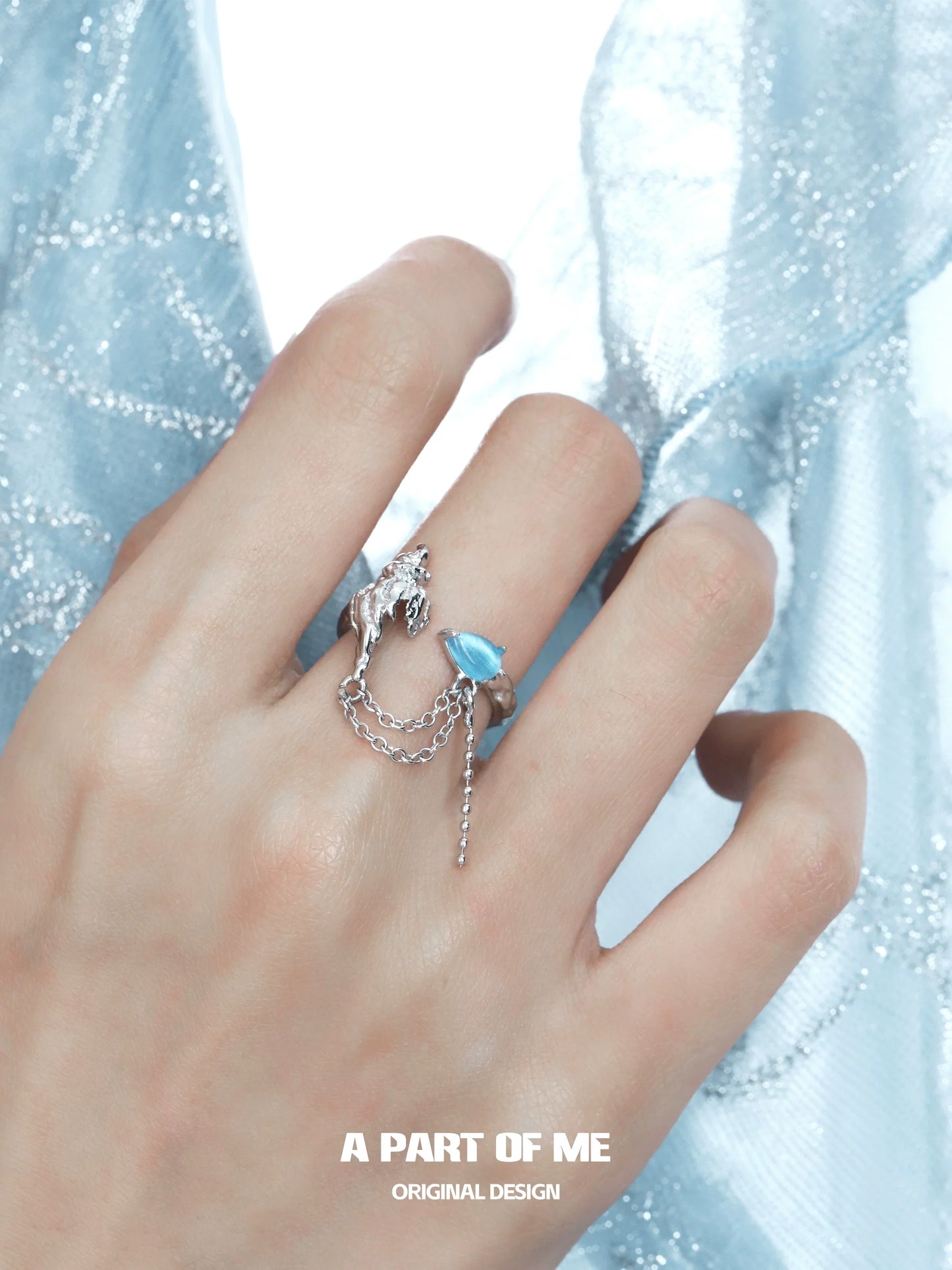 A PART OF ME silver ring featuring a blue conch chain ring design, elegantly worn on a hand