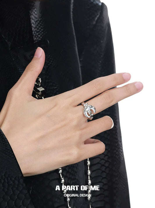 A hand wearing a bone orchid moon ring by A PART OF ME featuring a unique design and sparkling details