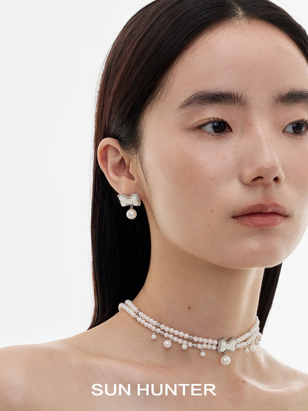 Elegant SUN HUNTER bow pearl earrings paired with a matching pearl necklace