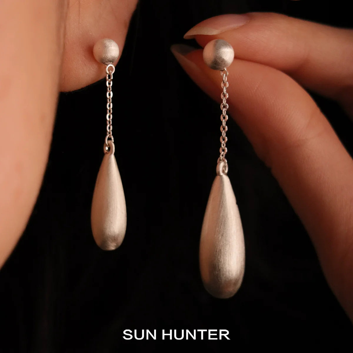Elegant SUN HUNTER brushed teardrop earrings with delicate chain detailing, perfect for casual or formal wear