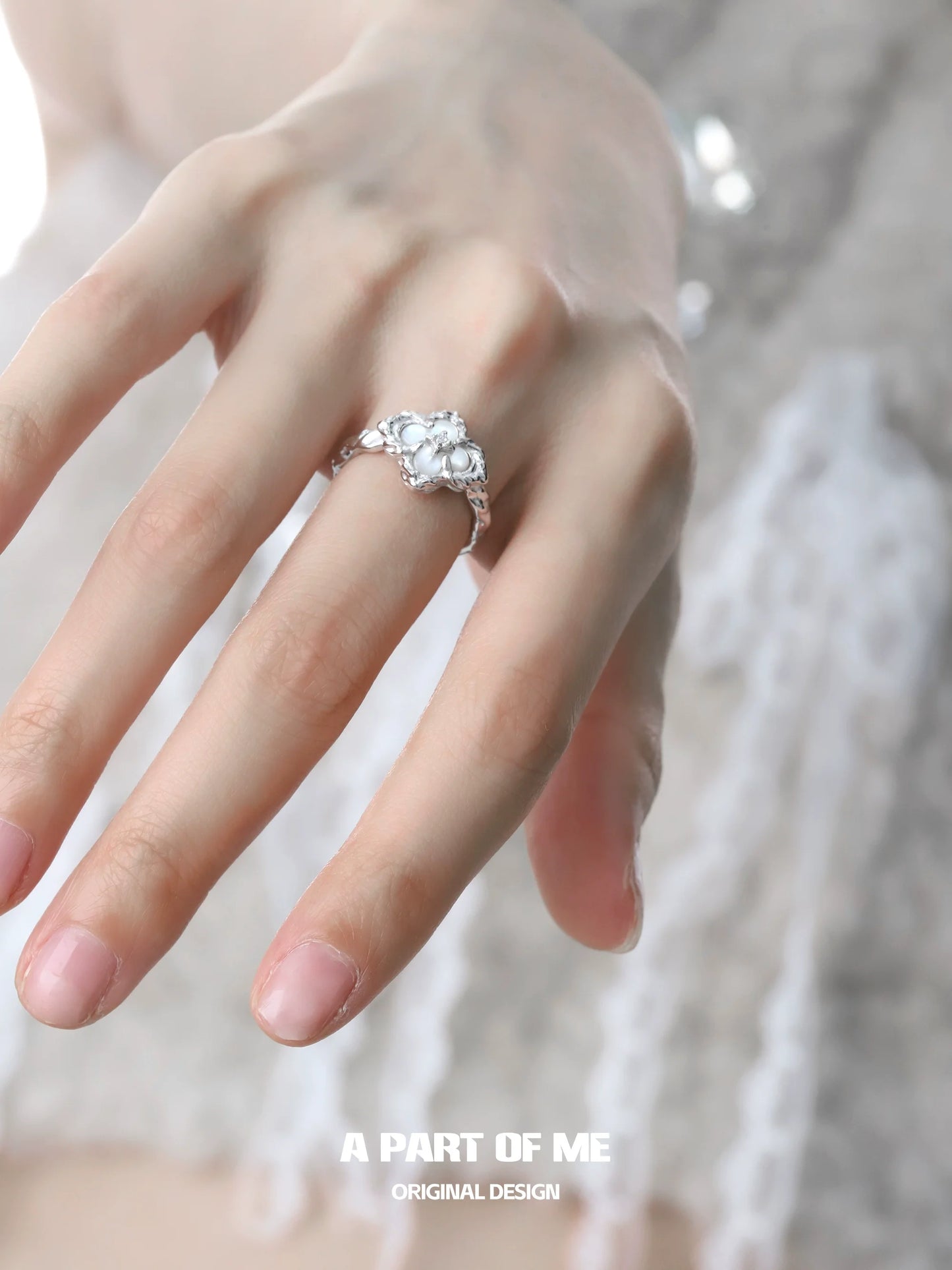 A hand wearing a butterfly clover silver ring with intricate design and sparkling gemstone accents