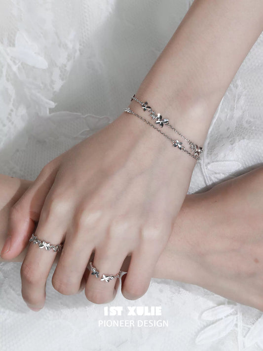Silver butterfly double chain bracelet showcased on a female wrist with stylish jewelry rings
