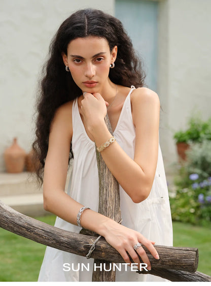 Model wearing a butterfly hollow ring and bracelets from SUN HUNTER in a garden setting
