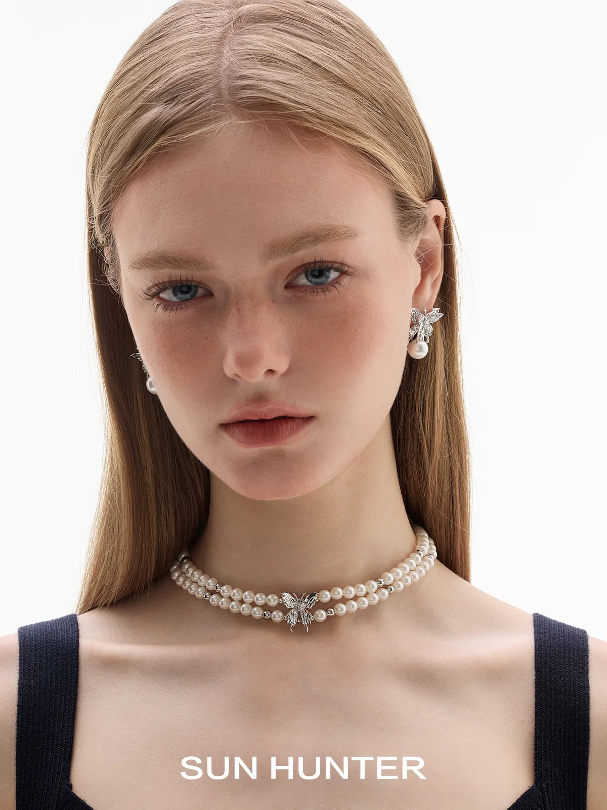 Elegant butterfly pearl earrings elegantly displayed on a model with a pearl choker necklace