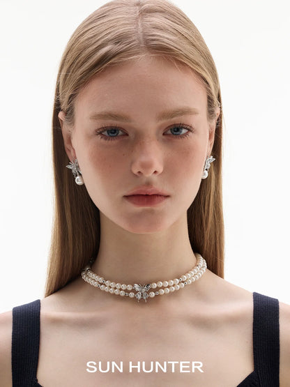 Model showcasing SUN HUNTER butterfly pearl earrings paired with a pearl choker necklace