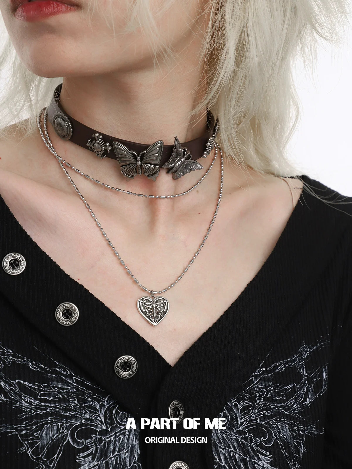 A PART OF ME butterfly punk necklace layered with a leather choker and silver chain for a stylish look