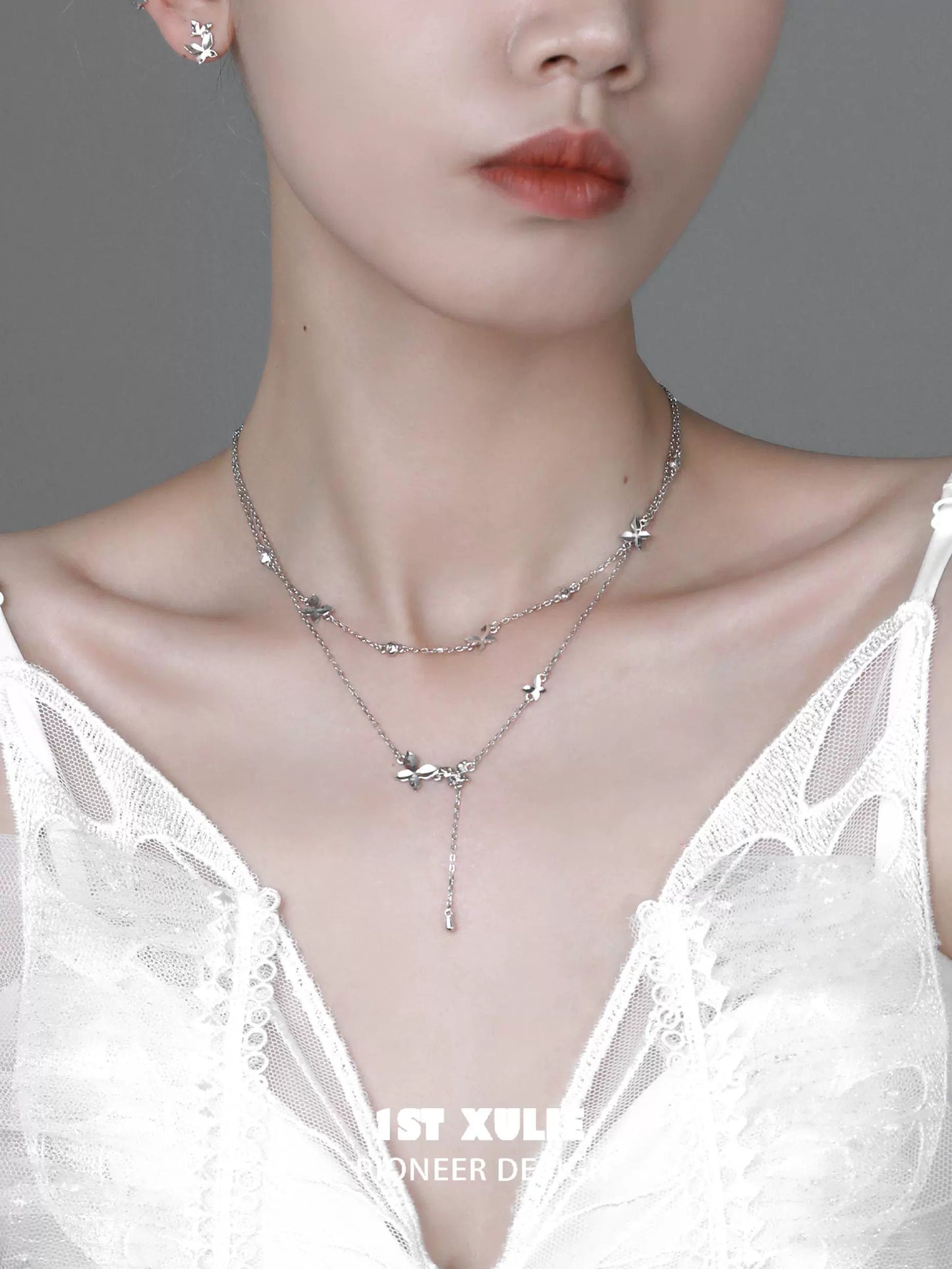 Elegant butterfly silver necklace layered design showcased on a model wearing a white dress
