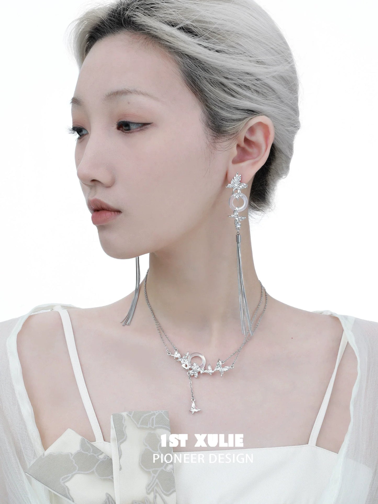 Elegant butterfly silver necklace worn by model with stylish earrings and chic outfit