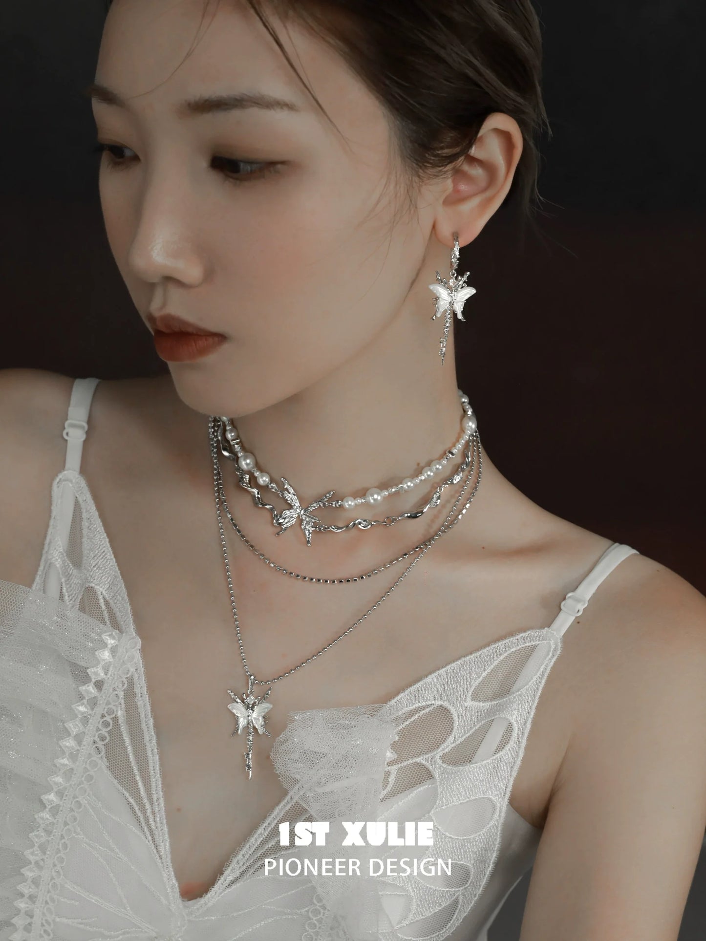 Model wearing butterfly tassel shell earrings with layered silver necklaces and a stylish outfit