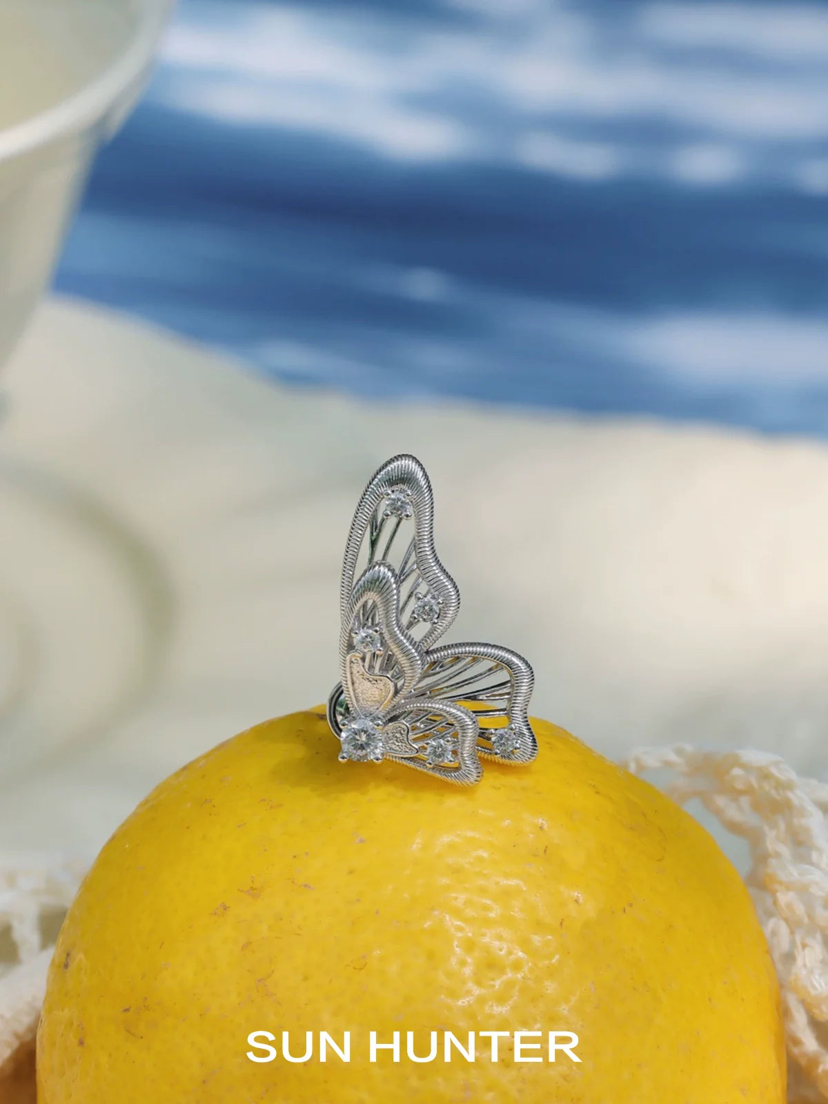 Elegant SUN HUNTER butterfly wing earrings showcased on a lemon for vibrant contrast