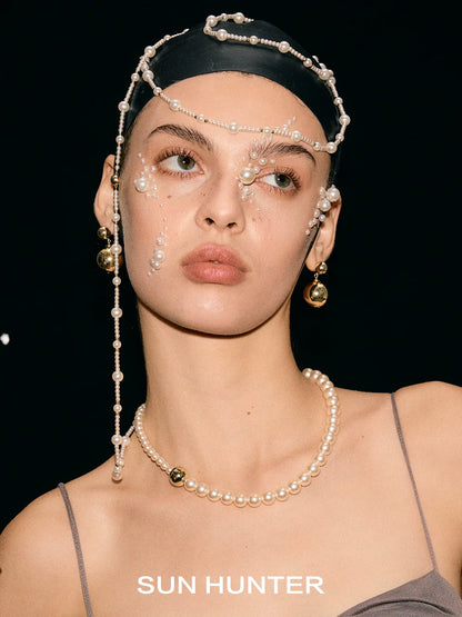 Elegant celestial planet gravity earrings from SUN HUNTER featured on a model with pearl accessories