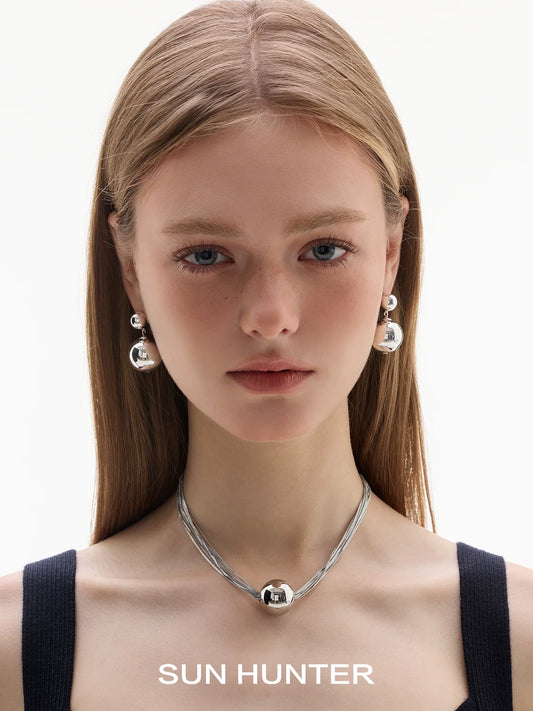 SUN HUNTER celestial planet gravity earrings in silver, elegantly worn by a model with long hair