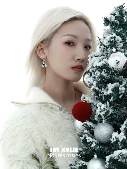 Stylish model wearing Christmas dog earrings next to a decorated holiday tree