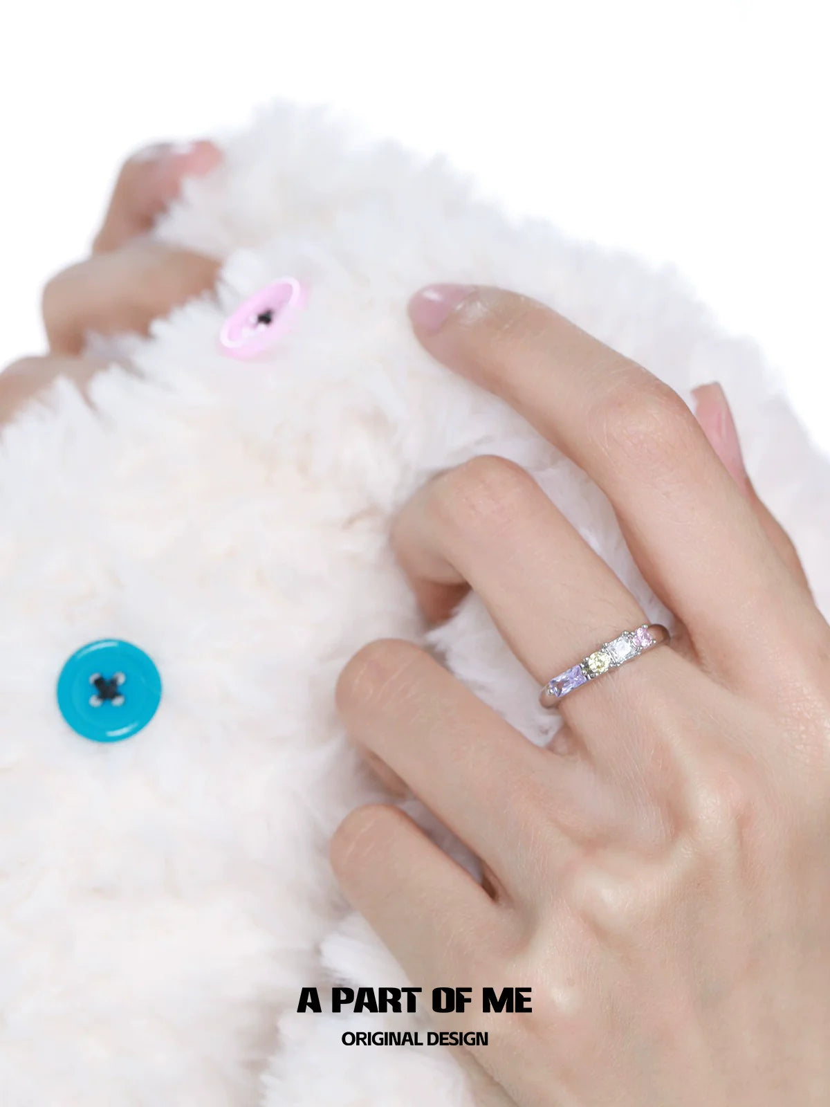 Colorful zircon ring worn on a hand, showcasing vibrant gemstones against a soft, textured background