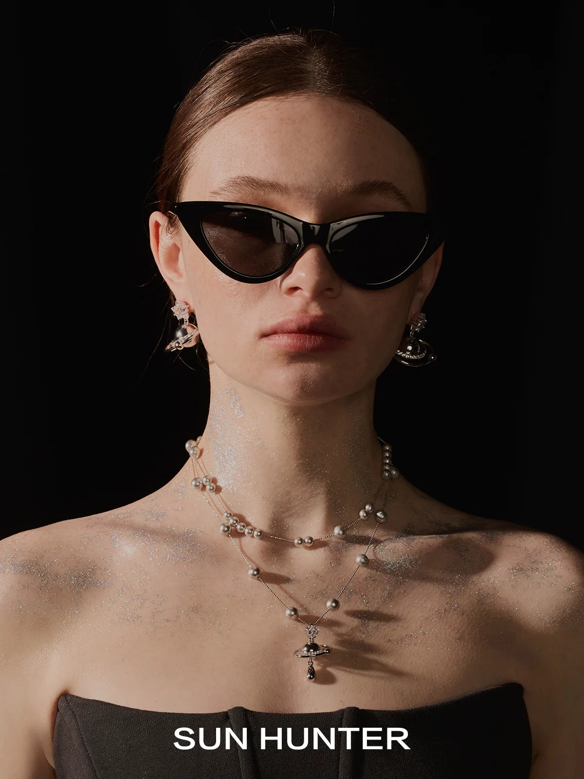 Stylish model wearing cosmic planet earrings set and black cat-eye sunglasses for a chic look