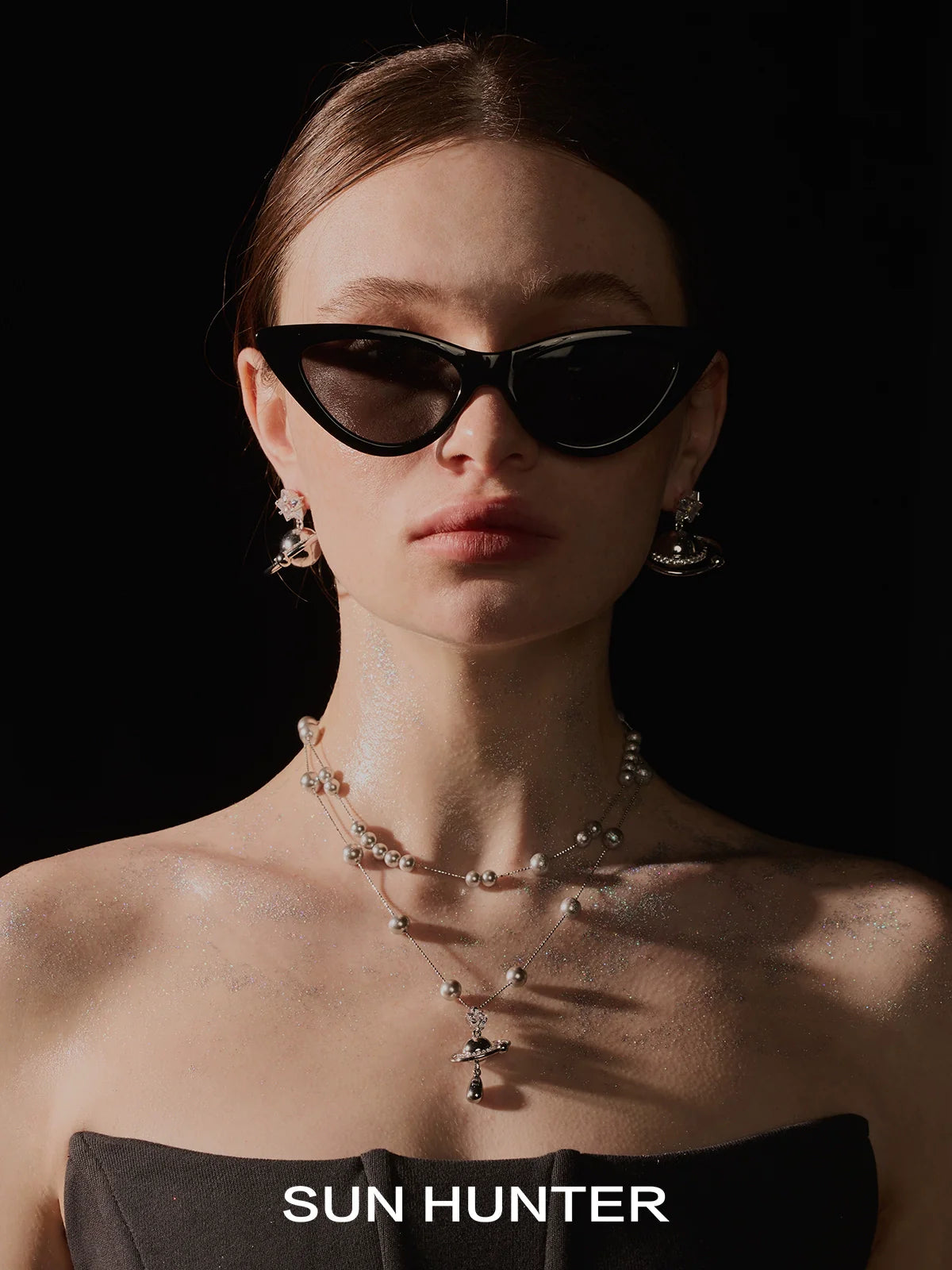 Model wearing SUN HUNTER cosmic planet star earrings with stylish black sunglasses