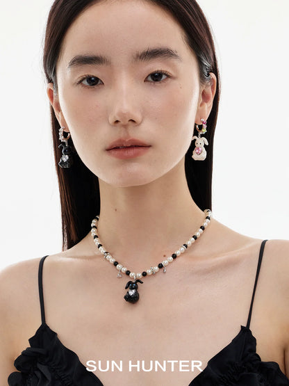 Cute enamel rabbit earrings by SUN HUNTER worn by a model with a pearl necklace
