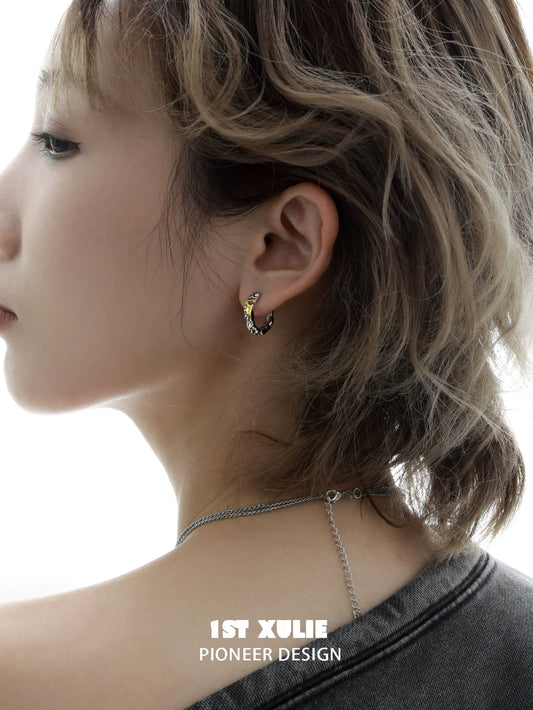 Edgy love letter earrings displayed on a model with short hair and a casual outfit
