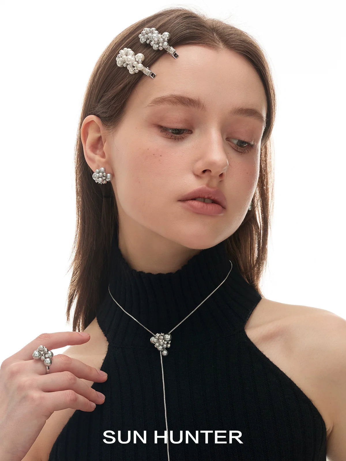 Elegant pearl statement ring worn by a model with matching pearl accessories and a black top