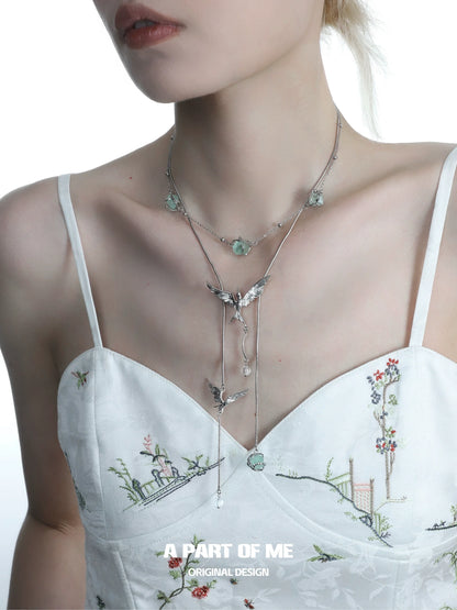 A PART OF ME flying bird fluorite necklace elegantly displayed on a model's neck against a floral outfit