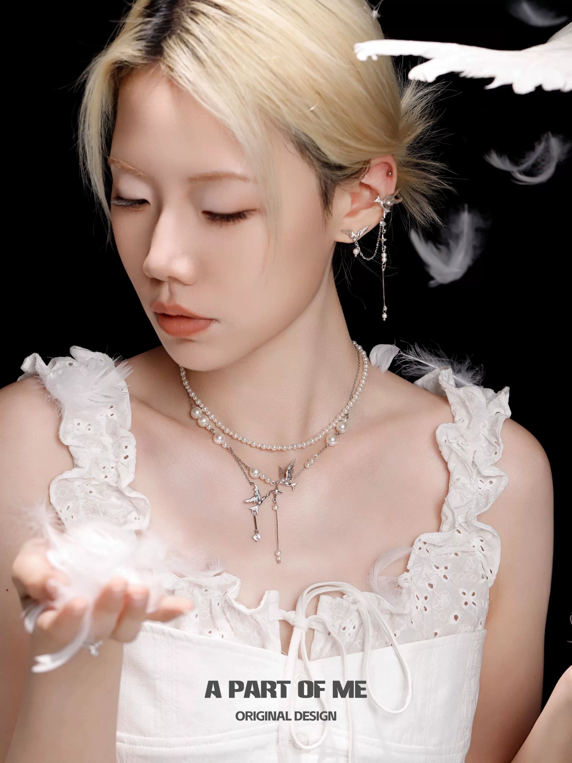Elegant flying bird pearl necklace by A PART OF ME, worn by a model in a white dress with feathers