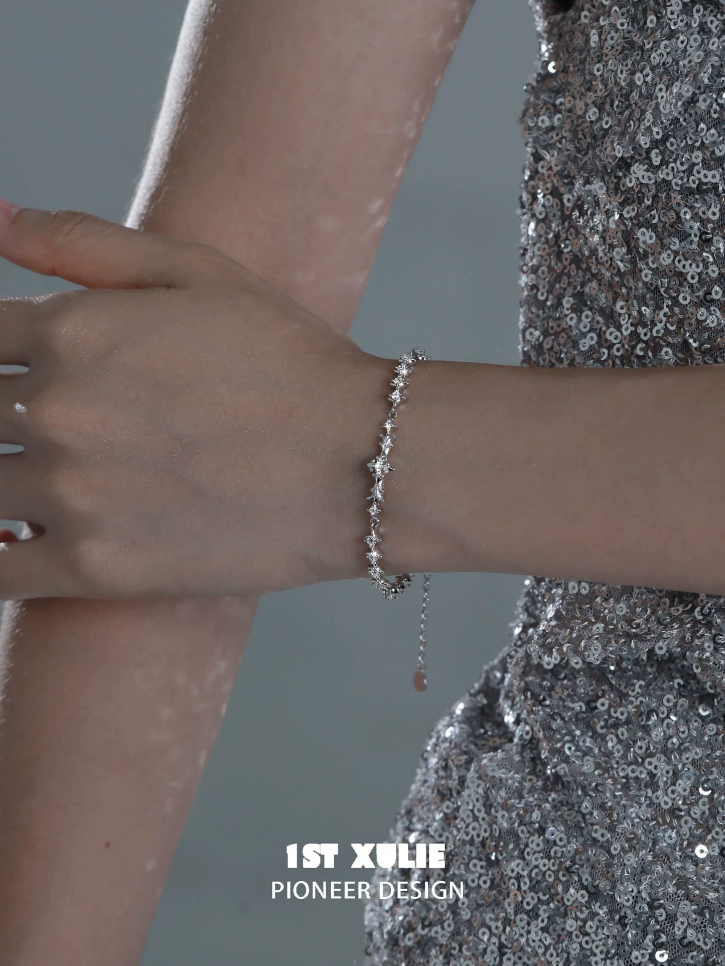 Elegant four-point star silver bracelet showcased on a model's wrist with a shiny background