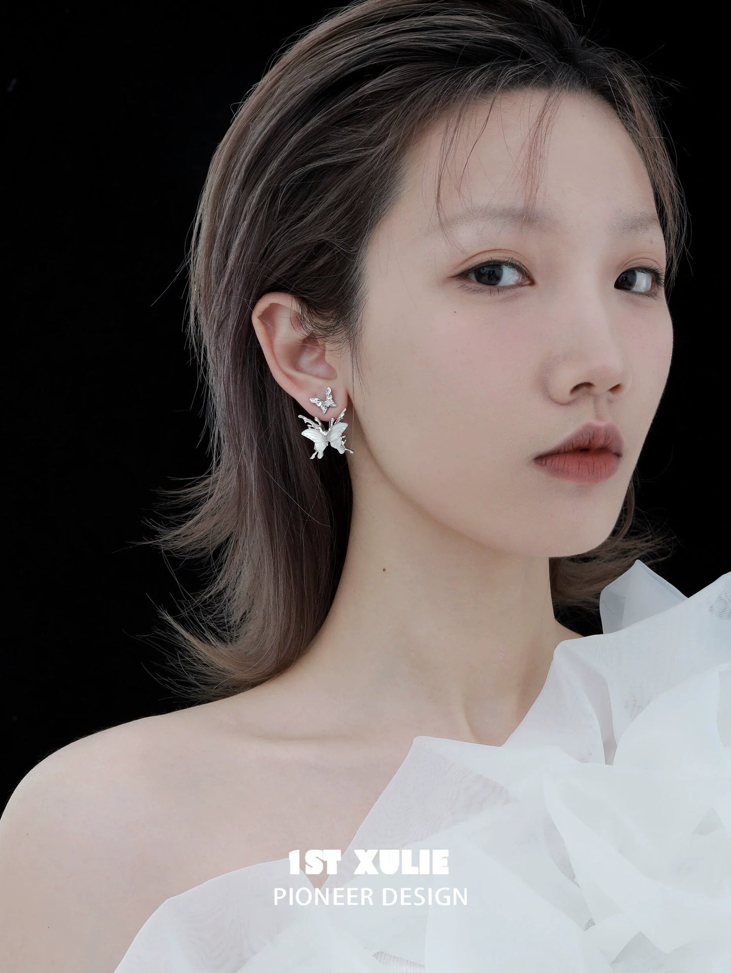 Futuristic butterfly earrings showcased on a model with elegant styling against a dark backdrop