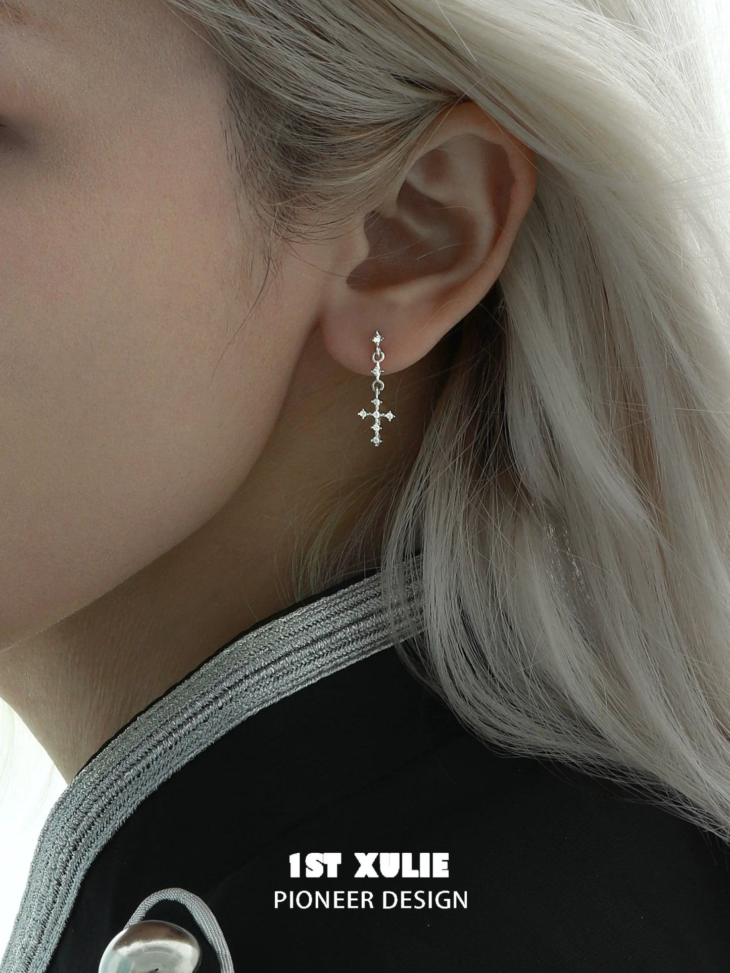 Elegant futuristic cross chain earrings worn by a model with platinum hair showcasing modern design