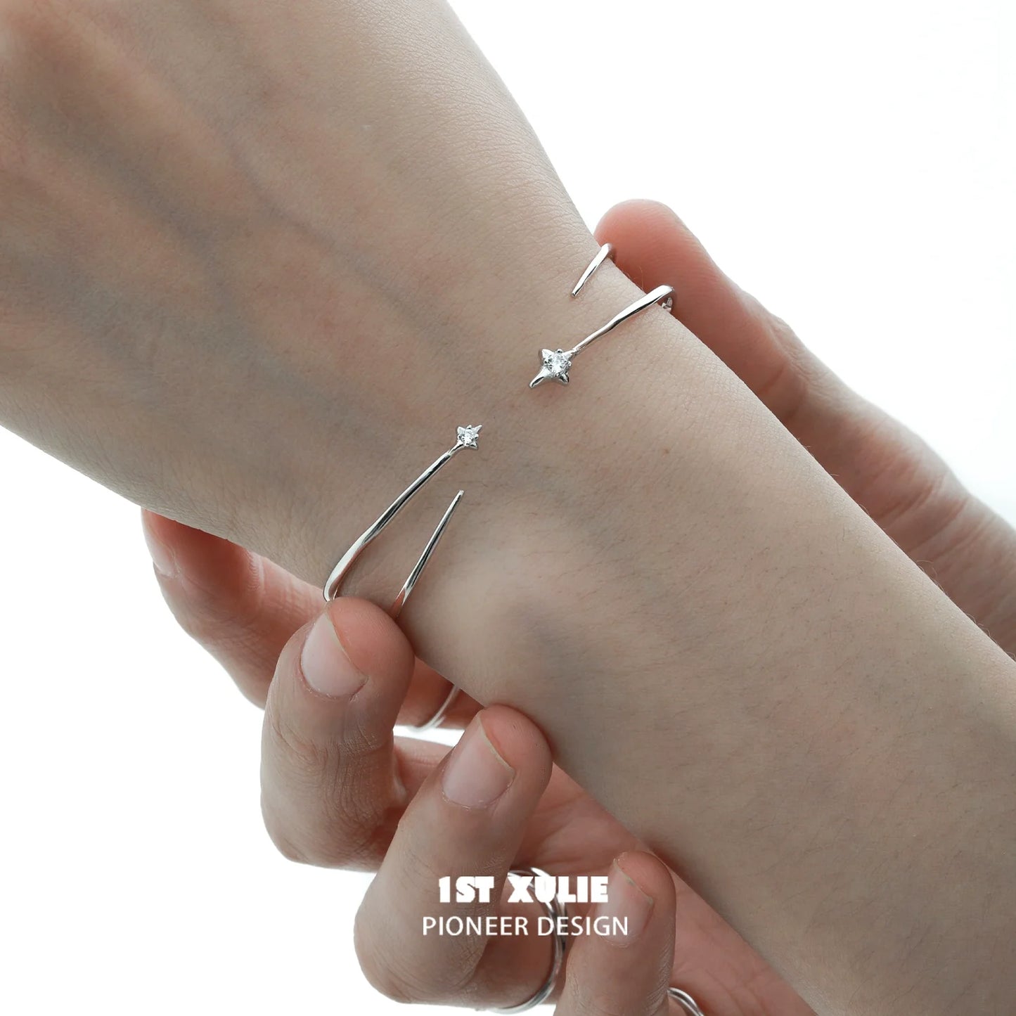 Minimalist design of a futuristic silver bracelet with delicate star accents on a wrist