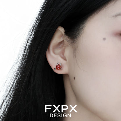 Close-up of bloody dragon claw gothic earrings worn on ear with black hair and pale skin