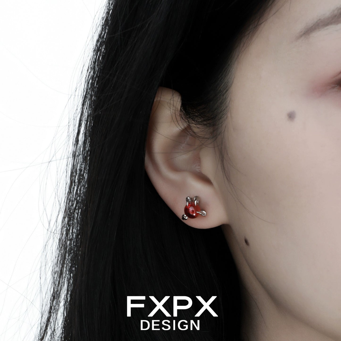 Close-up of bloody dragon claw gothic earrings worn on a person's ear with dark hair
