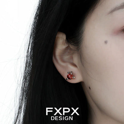 Close-up of bloody dragon claw gothic earrings worn on a person's ear with dark hair