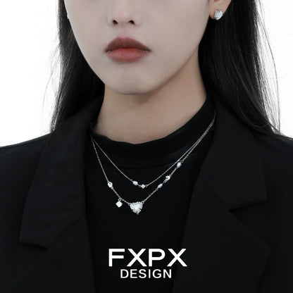 Stylish model wearing double layer silver love necklace with delicate charms and matching earrings