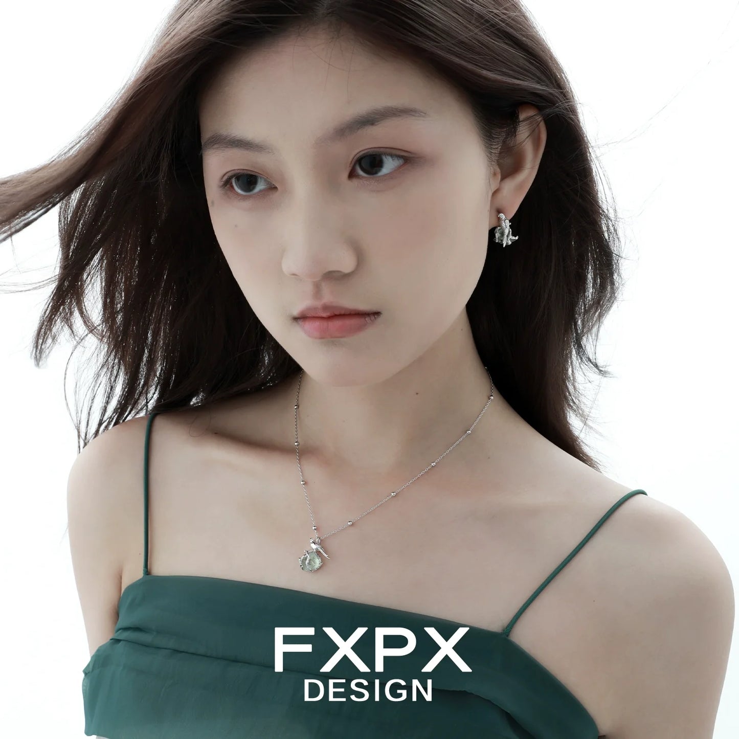 Woman wearing FXPX flying bird fluorite earrings paired with a stylish green dress