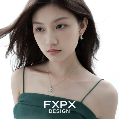 Woman wearing FXPX flying bird fluorite earrings paired with a stylish green dress