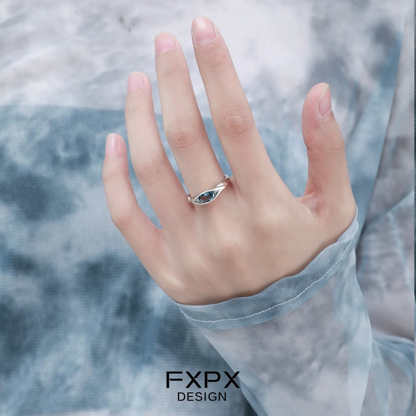 Elegant Iceland blue zircon ring worn on a hand with a stylish tie-dye shirt