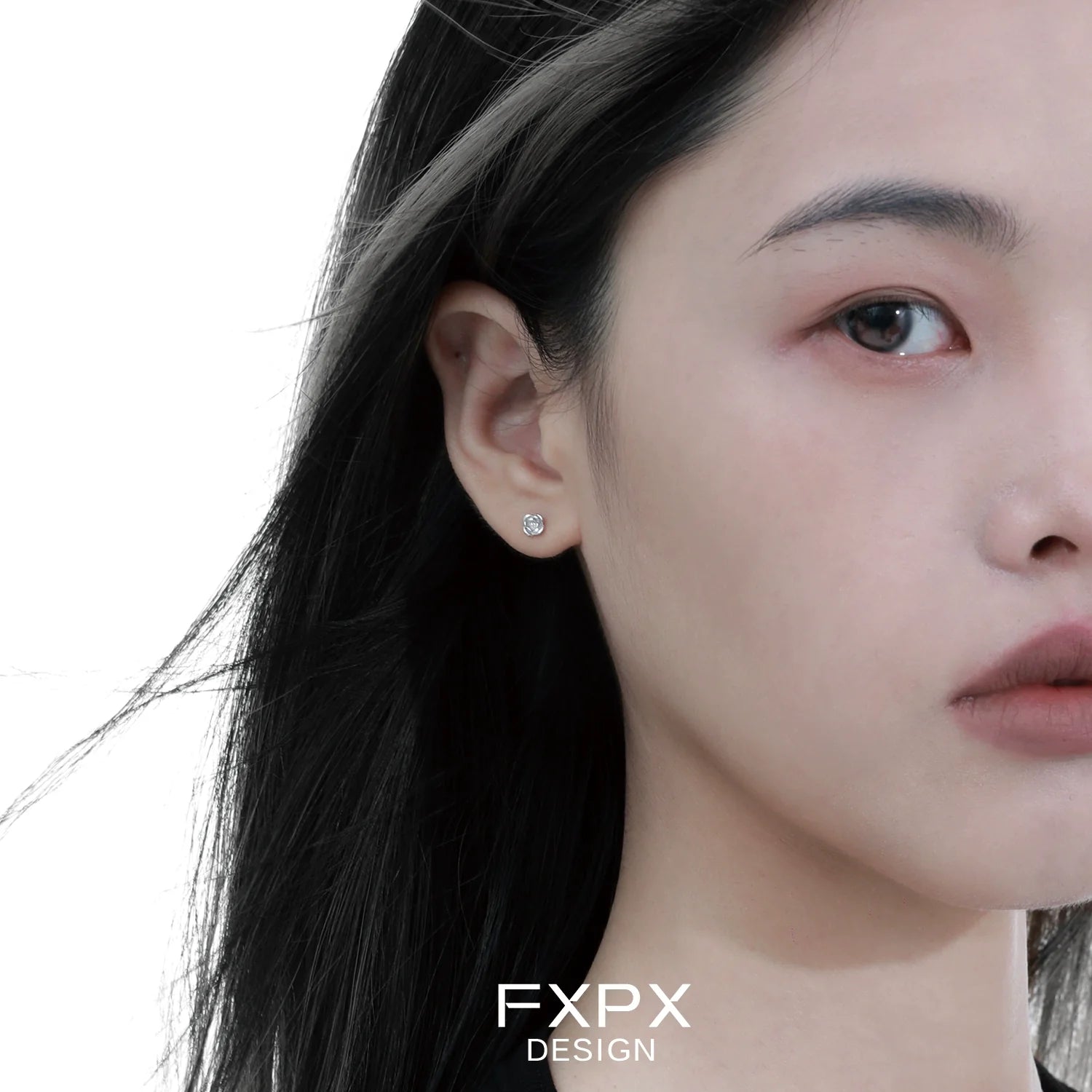 Minimal rose silver earrings showcased on a model's ear with sleek styling
