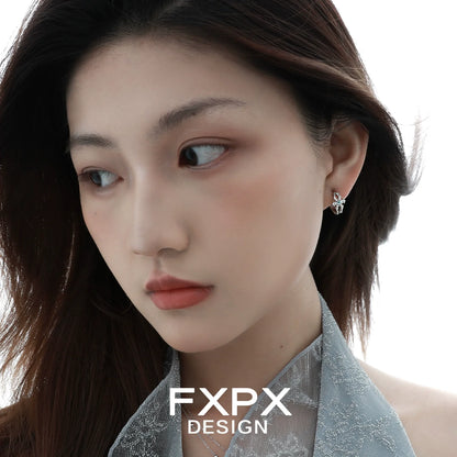 Elegant FXPX snowflake cross earrings shining on a model with long hair and soft makeup
