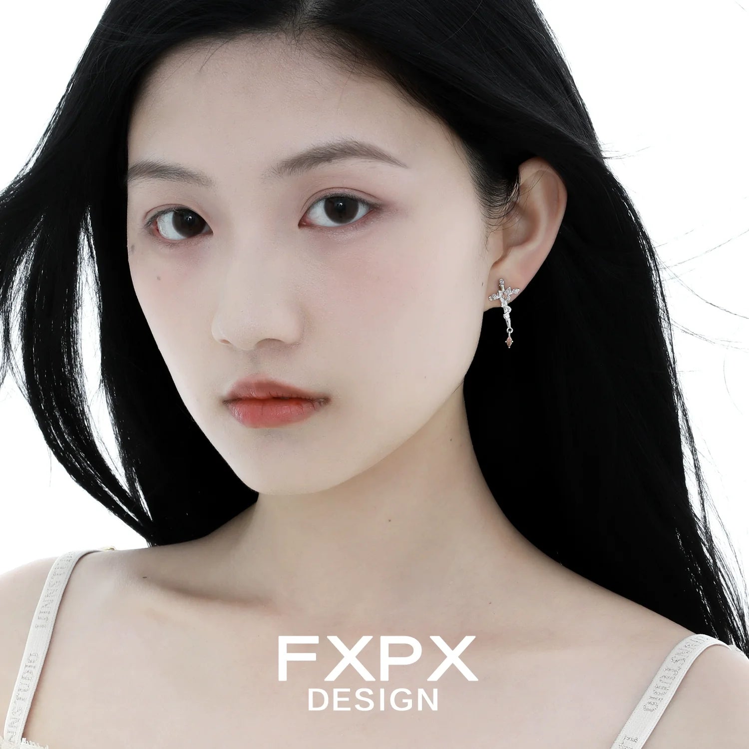 Elegant FXPX thorned butterfly cross earrings hanging on a model's ear with long hair flowing