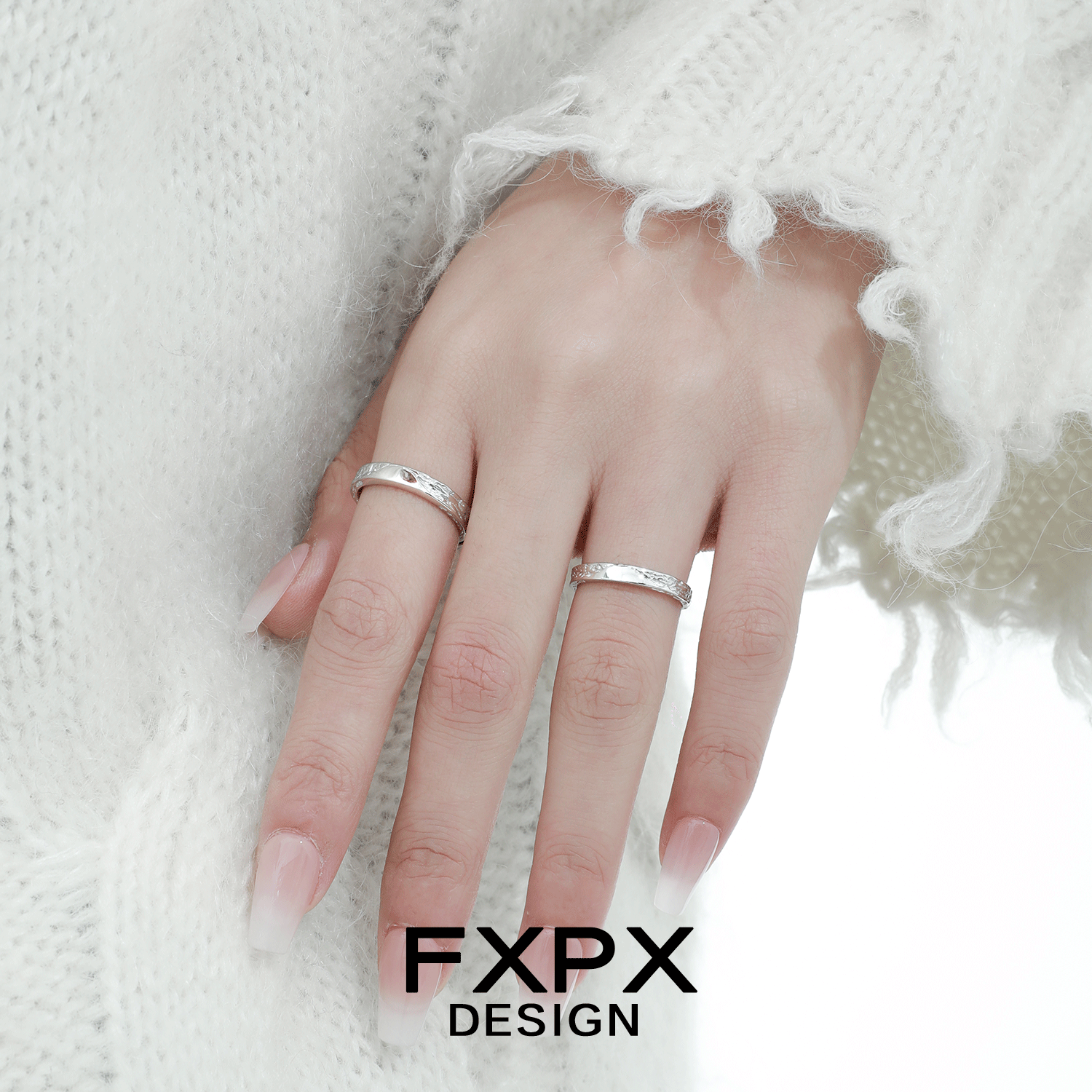 Unique couple rings by FXPX displayed on a hand wearing cozy white knit sweater
