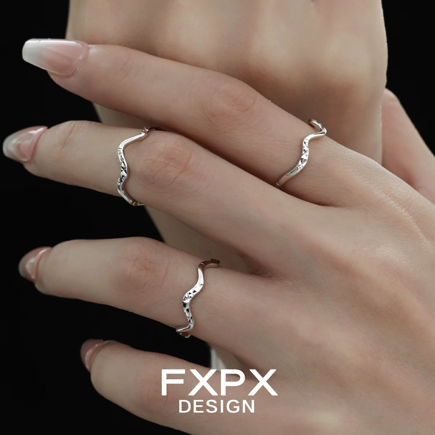 Three delicate wavy silver rings displayed on fingers, showcasing unique design by FXPX