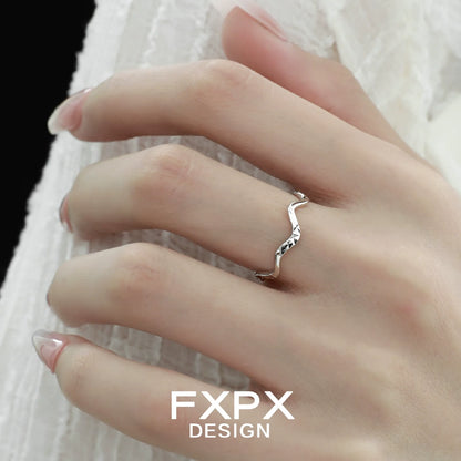 Elegant wavy silver ring showcased on a hand with manicured nails against a soft background