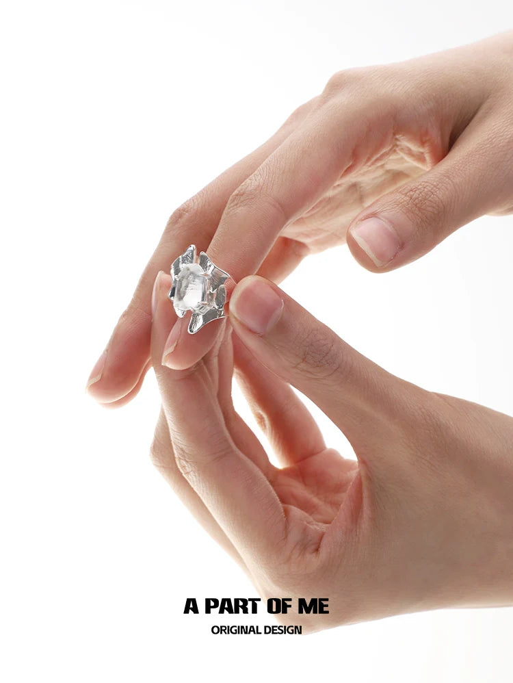 A geometric crystal punk ring held between two fingers, showcasing its unique design and clear crystal finish
