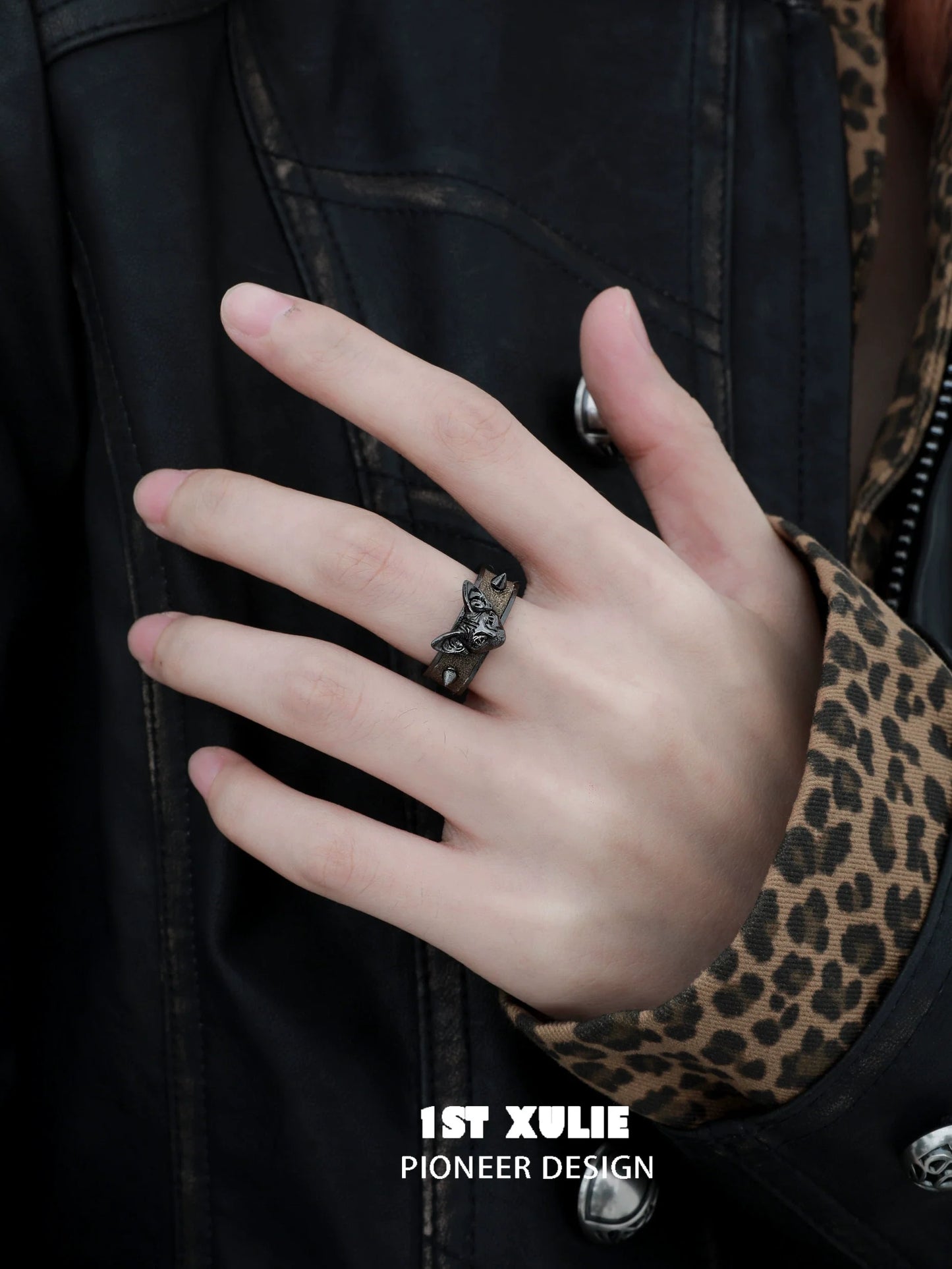 Gothic black cat ring on a hand, styled with a leather jacket and leopard print shirt