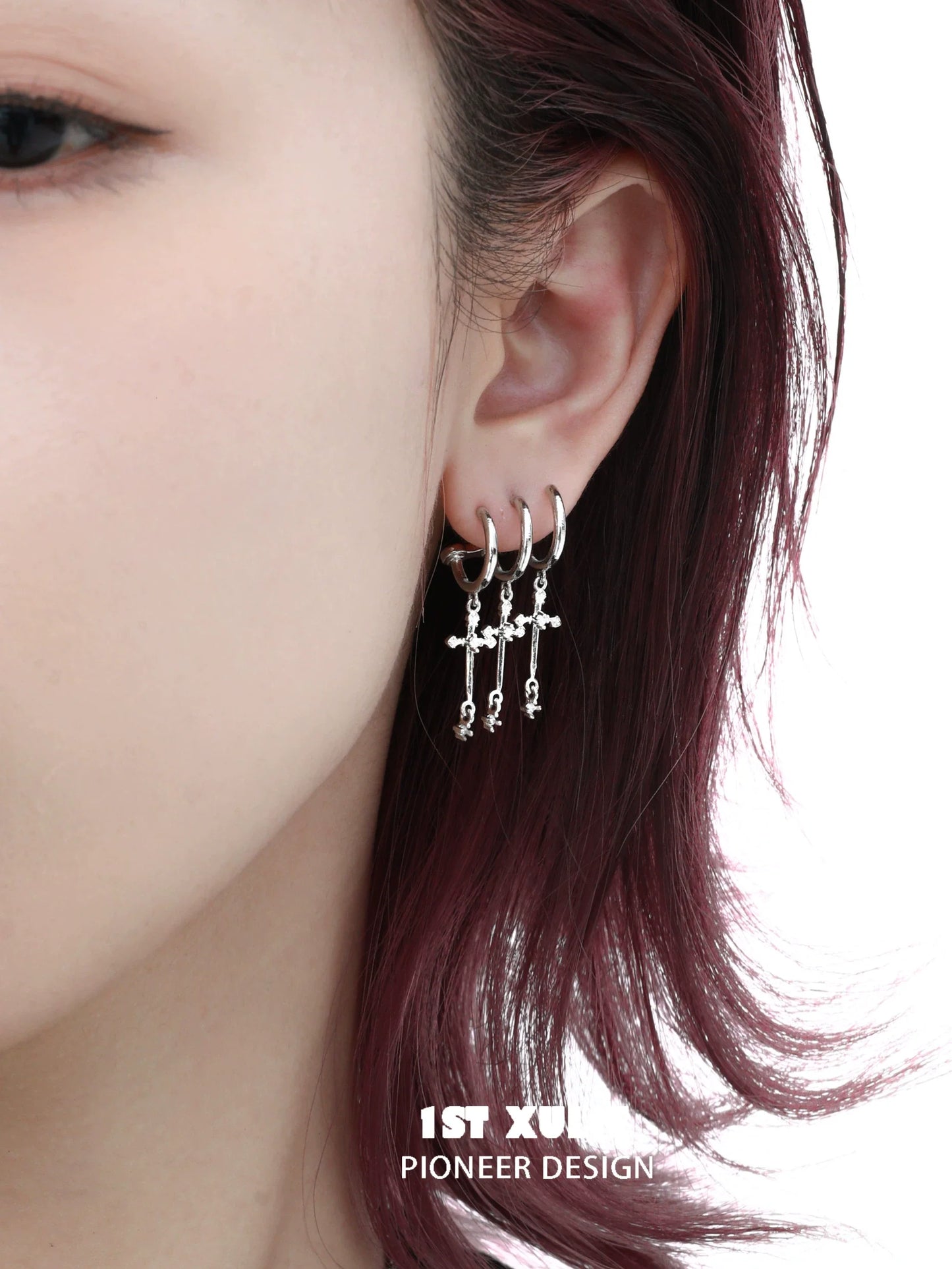 Gothic cross earrings in silver hanging elegantly on a model's ear for a stylish look