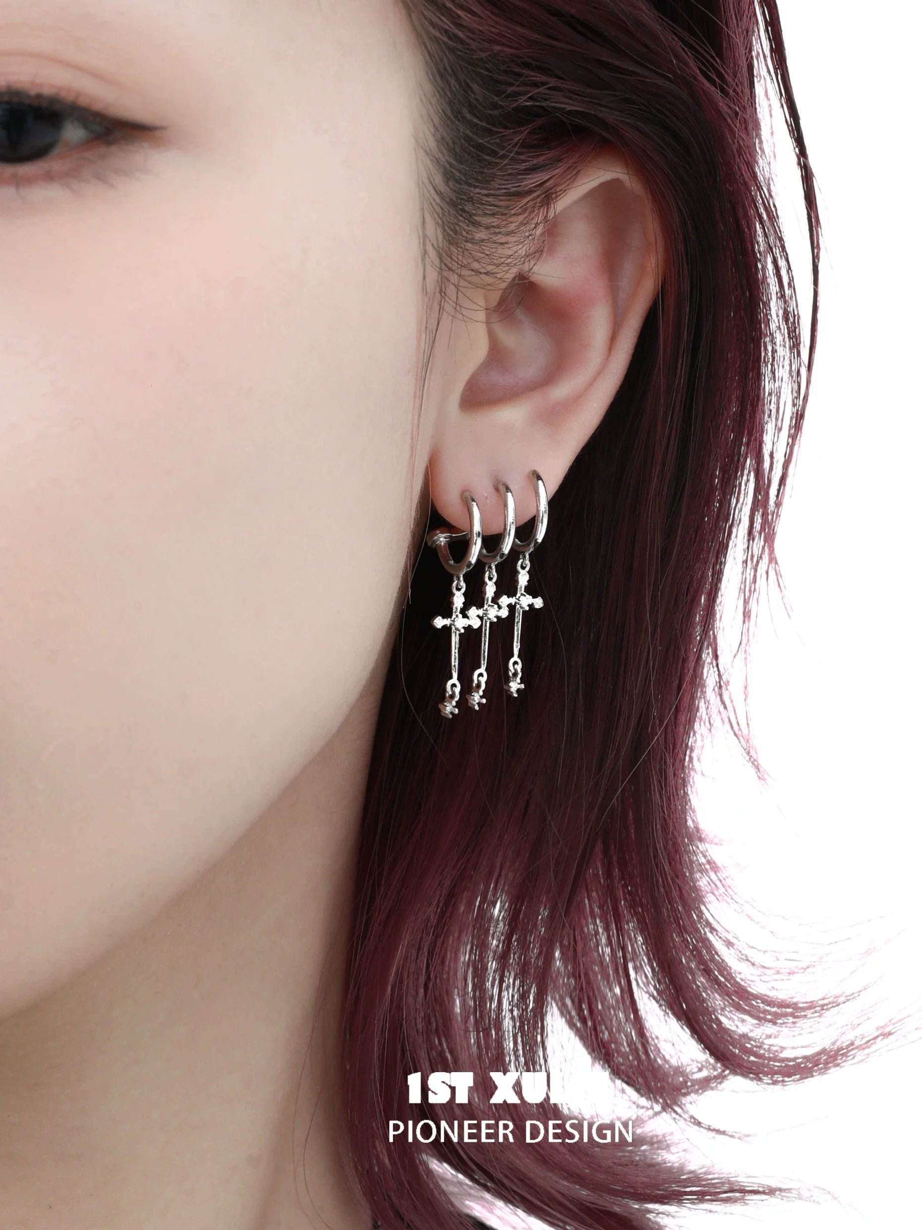 Gothic cross earrings in silver hanging elegantly on a model's ear for a stylish look
