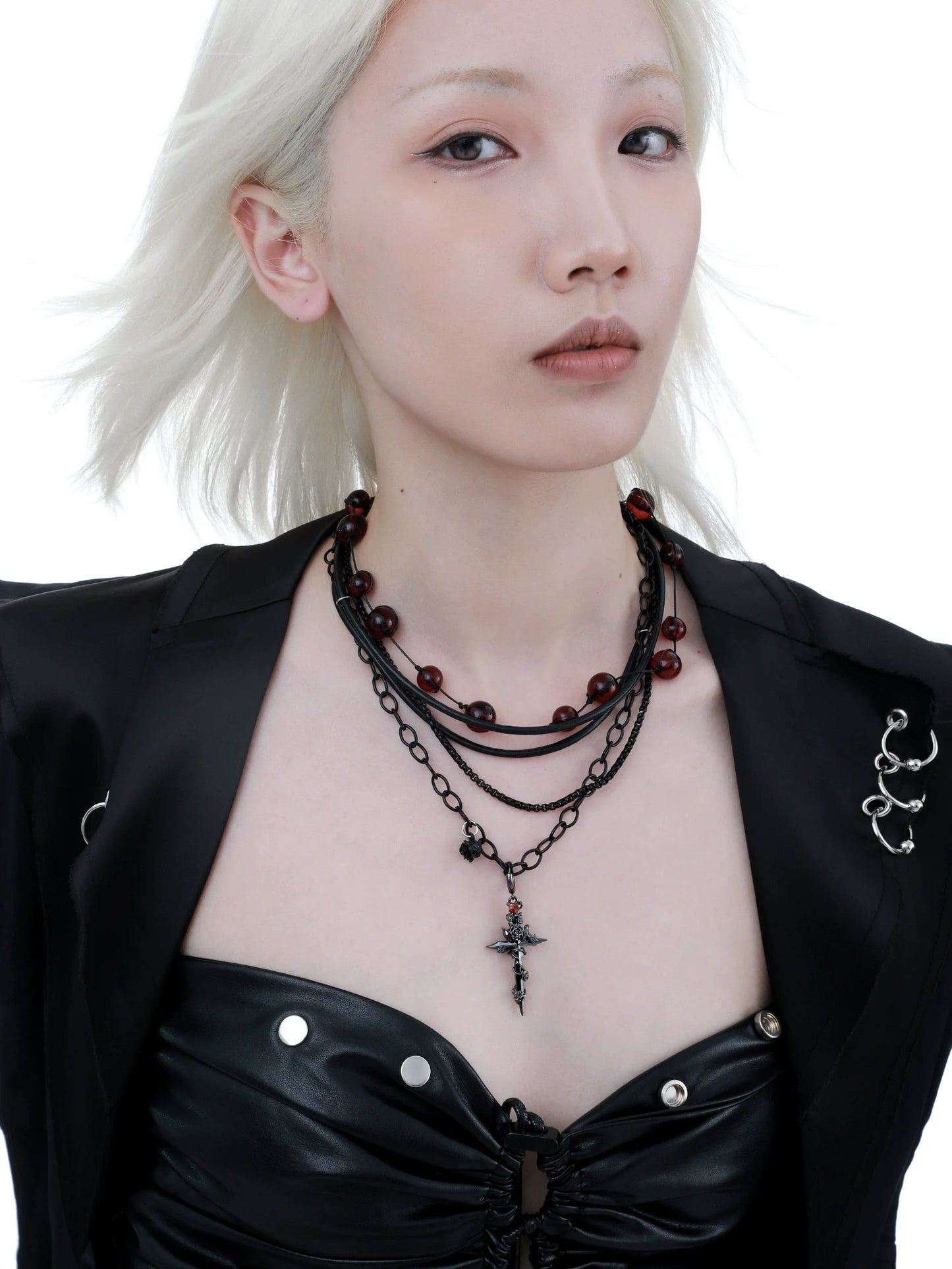 Gothic cross necklace featured on model with layered black chains and red beads for a striking look