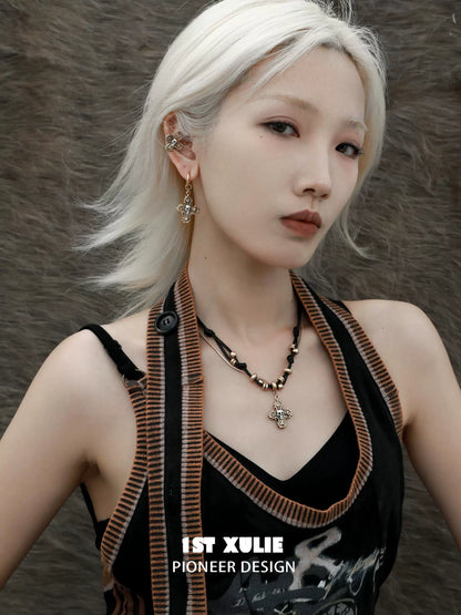 Fashion model wearing a gothic cross necklace paired with unique earrings and stylish attire