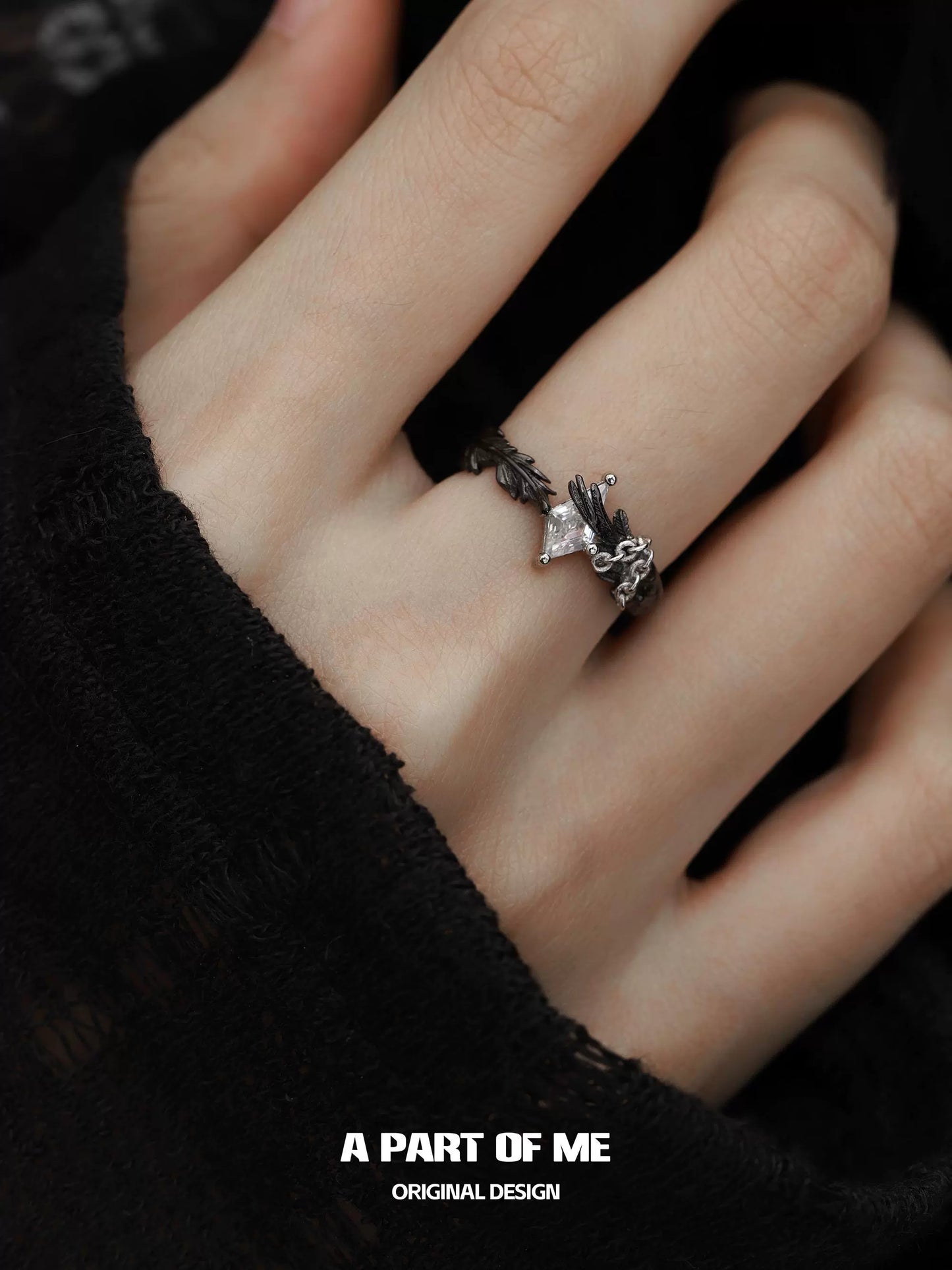 A gothic feather ring by A PART OF ME featuring intricate detailing on a worn hand
