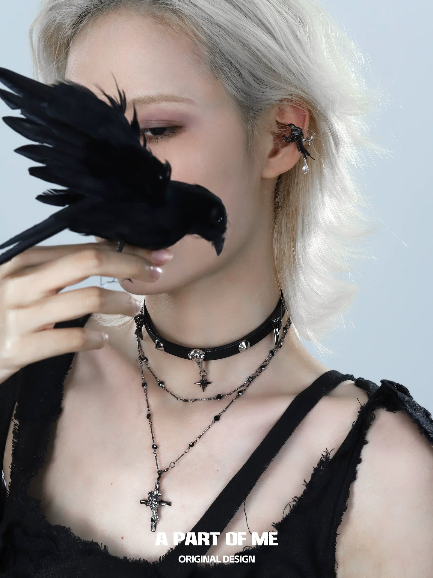 Gothic raven cross necklace layered with a choker and worn by a model with a black bird.